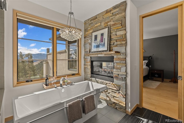 15077 Wilson Peak Rd, Pine, CO 80470 - ensuite bathroom featuring a soaking tub, a chandelier, tile patterned flooring, a mountain view, and a stone fireplace