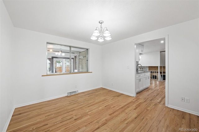 8793 E Monmouth Pl, Denver, CO 80237 - spare room with a chandelier, light wood-style floors, baseboards, and a sink