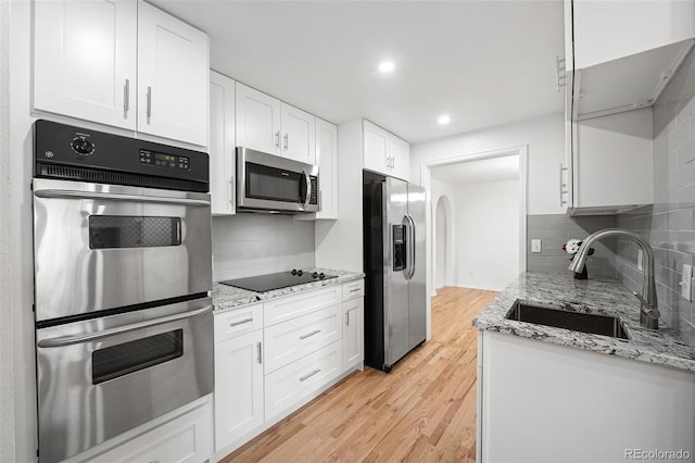 8793 E Monmouth Pl, Denver, CO 80237 - kitchen with appliances with stainless steel finishes, a sink, backsplash, light wood finished floors, and white cabinets