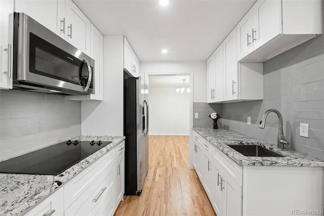 8793 E Monmouth Pl, Denver, CO 80237 - kitchen featuring appliances with stainless steel finishes, a sink, backsplash, light wood finished floors, and recessed lighting