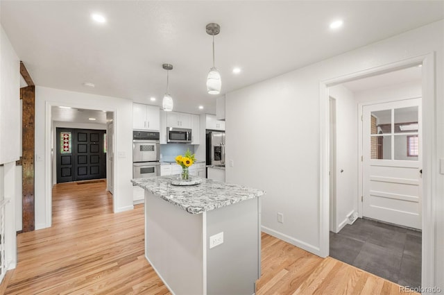 8793 E Monmouth Pl, Denver, CO 80237 - kitchen featuring stainless steel appliances, a kitchen island, recessed lighting, white cabinetry, and light wood-style flooring
