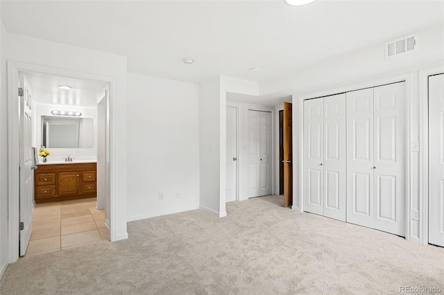 8793 E Monmouth Pl, Denver, CO 80237 - unfurnished bedroom with light colored carpet, two closets, baseboards, ensuite bathroom, and a sink