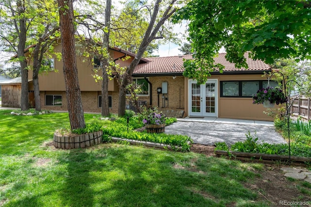 8793 E Monmouth Pl, Denver, CO 80237 - back of house featuring a lawn, french doors, brick siding, a tile roof, and a patio