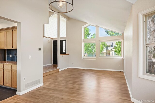 7582 Powderhorn Dr, Lone Tree, CO 80124 - unfurnished living room featuring a chandelier, light wood finished floors, baseboards, and high vaulted ceiling