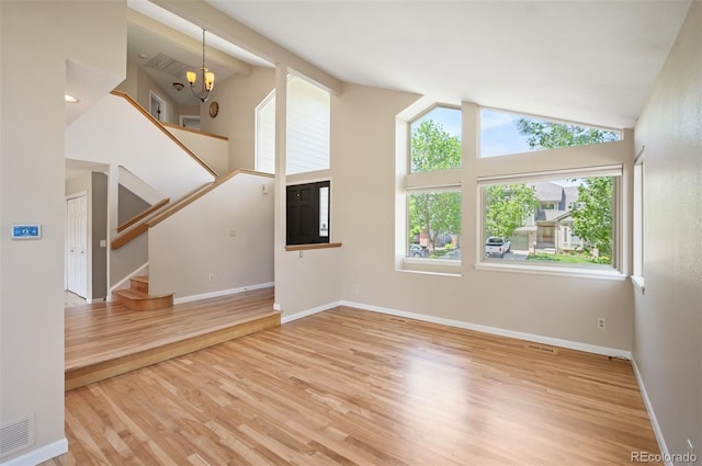 7582 Powderhorn Dr, Lone Tree, CO 80124 - unfurnished living room with stairway, wood finished floors, baseboards, high vaulted ceiling, and a chandelier