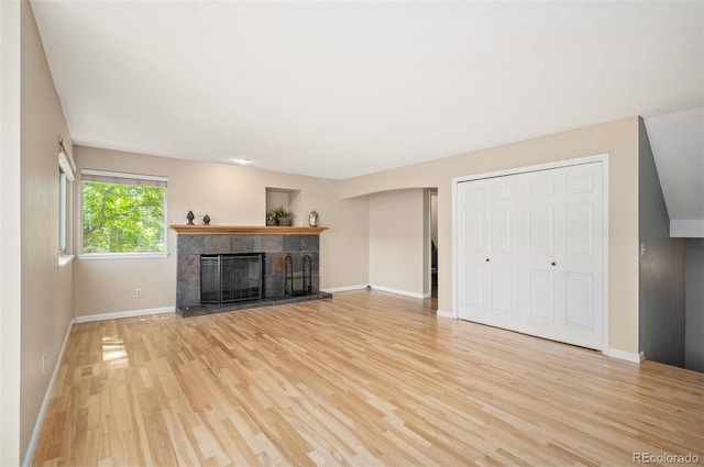 7582 Powderhorn Dr, Lone Tree, CO 80124 - unfurnished living room featuring a tiled fireplace, light wood-type flooring, and baseboards