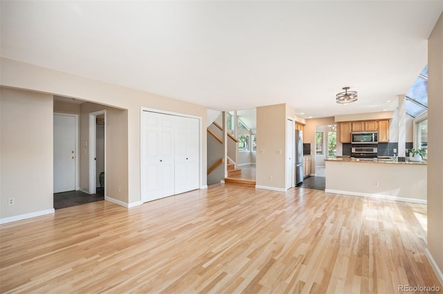 7582 Powderhorn Dr, Lone Tree, CO 80124 - unfurnished living room featuring stairway, light wood finished floors, and baseboards