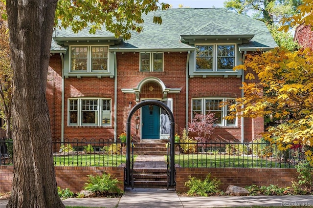 view of front of property with a fenced front yard, roof with shingles, and brick siding