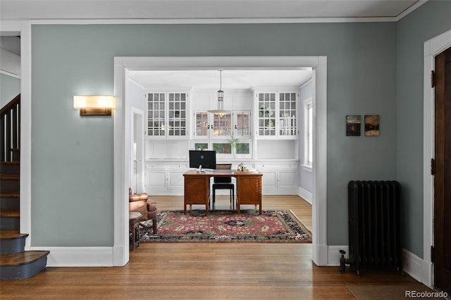 home office featuring radiator heating unit, crown molding, baseboards, and wood finished floors