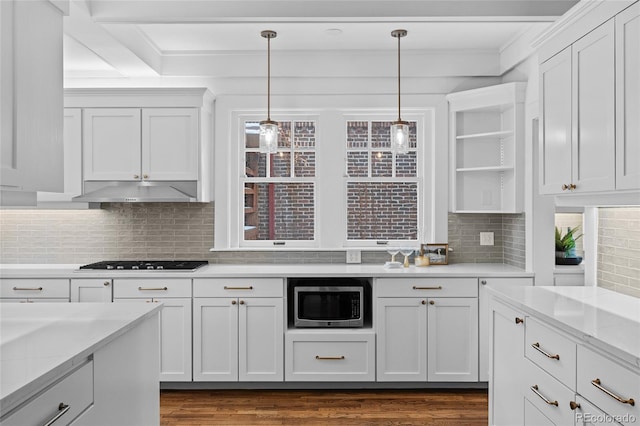 kitchen featuring under cabinet range hood, black cooktop, open shelves, stainless steel microwave, and pendant lighting