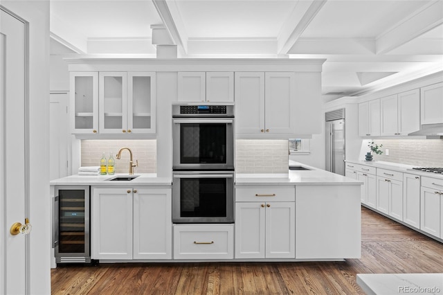 kitchen featuring beverage cooler, dark wood finished floors, a sink, stainless steel appliances, and beam ceiling