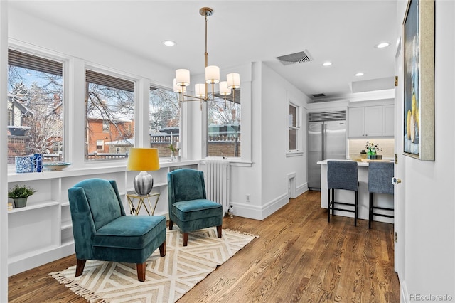 living area with a notable chandelier, recessed lighting, visible vents, wood finished floors, and baseboards