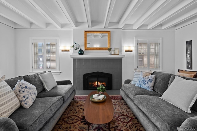 living room with beamed ceiling, a fireplace with flush hearth, and a healthy amount of sunlight