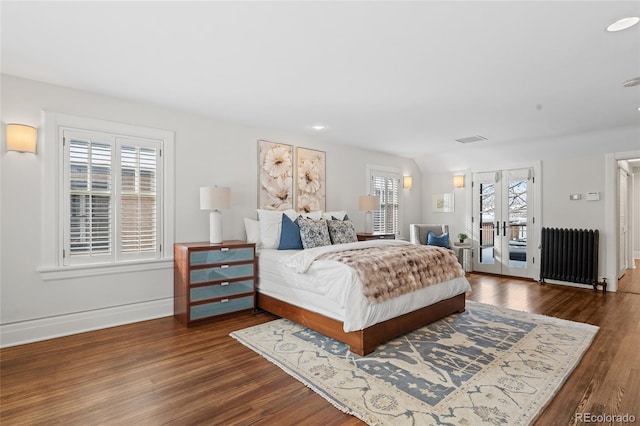 bedroom with access to exterior, multiple windows, radiator heating unit, and wood finished floors