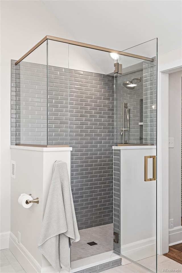 bathroom with a shower stall and baseboards