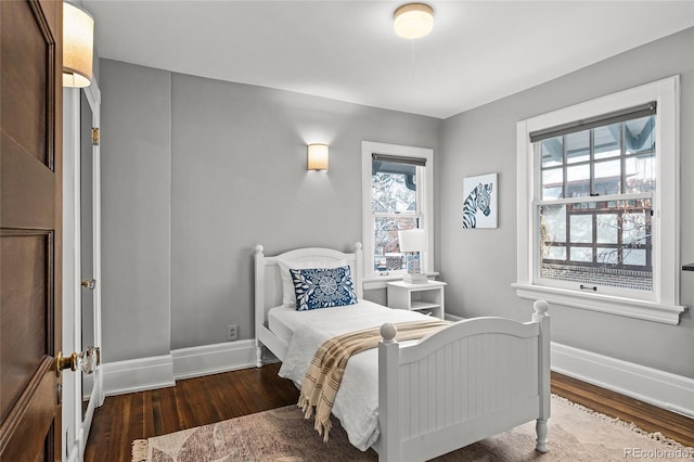 bedroom featuring multiple windows, baseboards, and wood finished floors