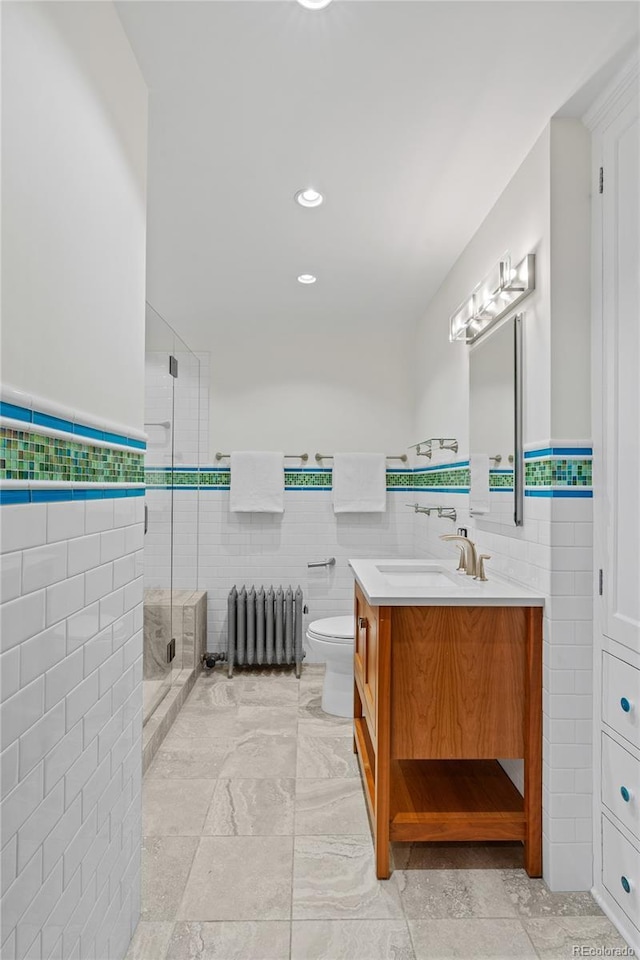 bathroom with toilet, vanity, tile walls, a stall shower, and radiator heating unit