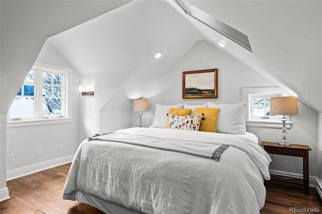 bedroom featuring vaulted ceiling with skylight, wood finished floors, and baseboards