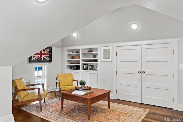 living area featuring vaulted ceiling, dark wood-type flooring, and baseboards