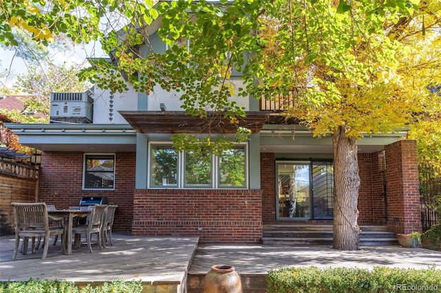 back of house featuring entry steps, outdoor dining area, brick siding, and central AC unit