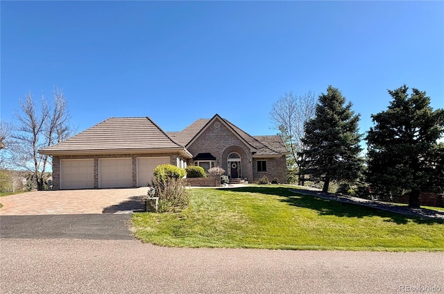ranch-style home featuring driveway, a tile roof, a front yard, and a garage