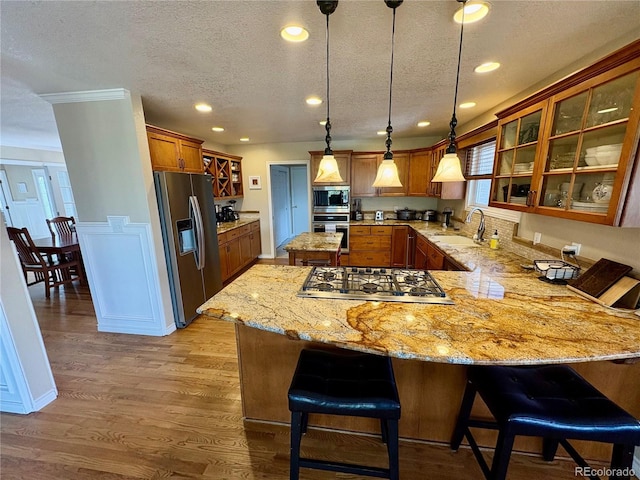 kitchen with a sink, appliances with stainless steel finishes, a peninsula, and a textured ceiling