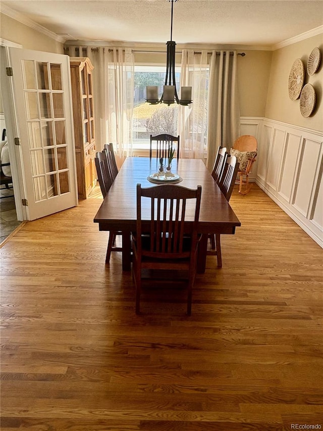dining room with ornamental molding, wainscoting, and wood finished floors