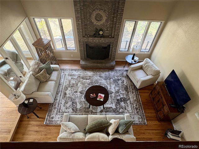 living room with a brick fireplace, baseboards, and wood finished floors