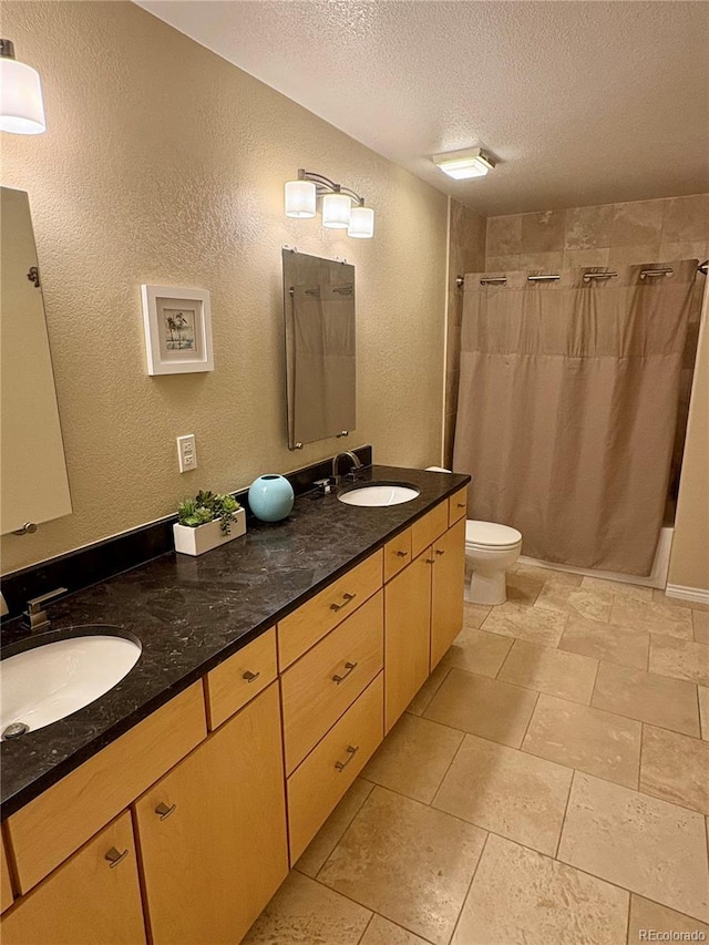 full bath featuring a sink, a shower with curtain, a textured wall, and a textured ceiling