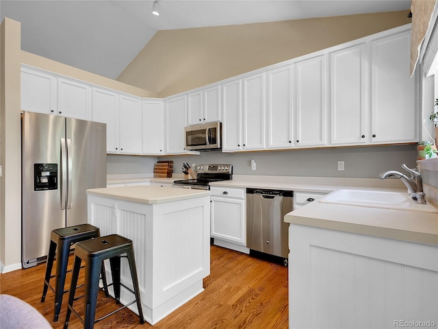 1234 Riddlewood Ln, Highlands Ranch, CO 80129 - kitchen with stainless steel appliances, vaulted ceiling, white cabinetry, a kitchen island, and light countertops