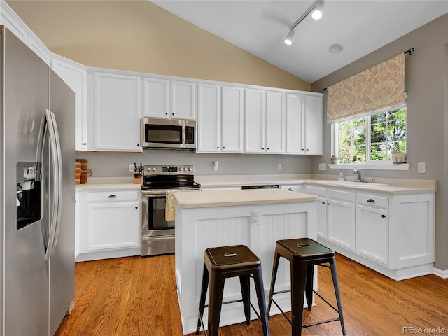 1234 Riddlewood Ln, Highlands Ranch, CO 80129 - kitchen featuring appliances with stainless steel finishes, vaulted ceiling, a kitchen island, light countertops, and white cabinets