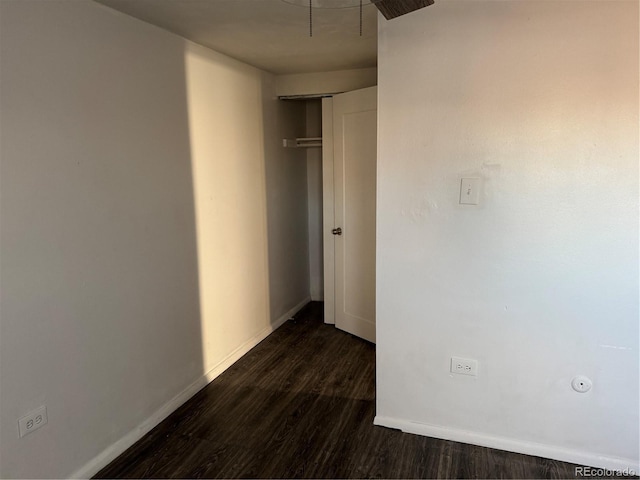 unfurnished bedroom featuring baseboards, dark wood finished floors, and a closet