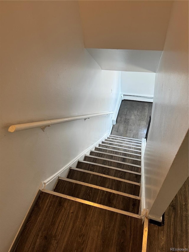 stairs featuring baseboard heating, wood finished floors, and baseboards