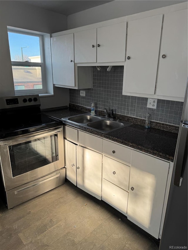 kitchen featuring dark countertops, white cabinets, stainless steel range with electric cooktop, and a sink