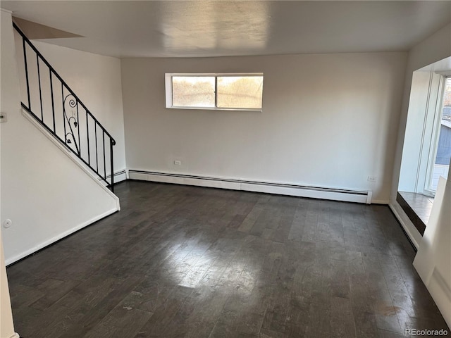 spare room with stairs, dark wood-type flooring, and a baseboard radiator