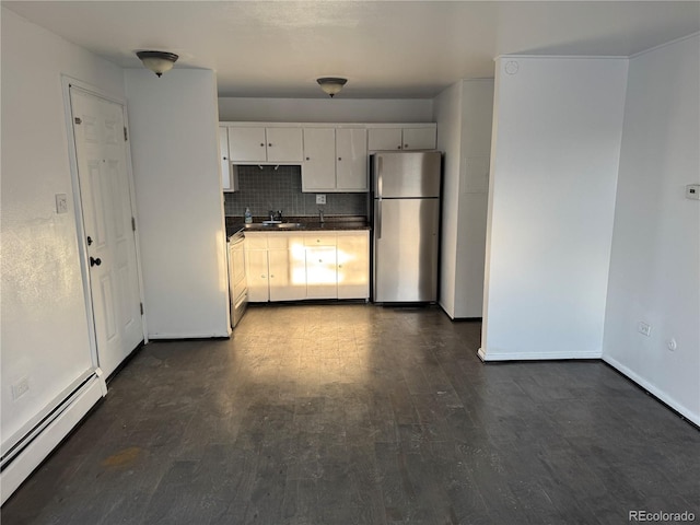 kitchen with tasteful backsplash, dark countertops, a baseboard heating unit, freestanding refrigerator, and dark wood-type flooring