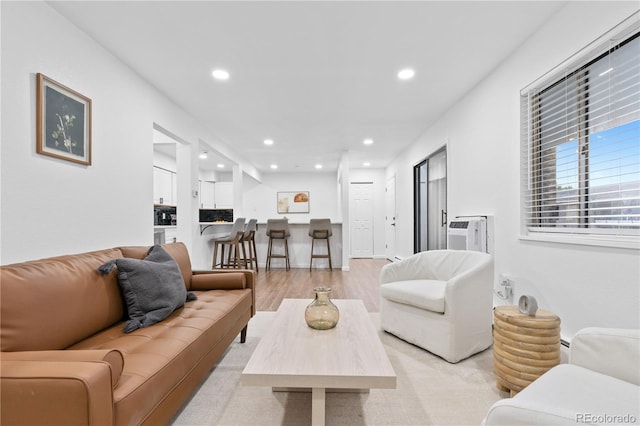 living room featuring a wall mounted air conditioner and light hardwood / wood-style flooring