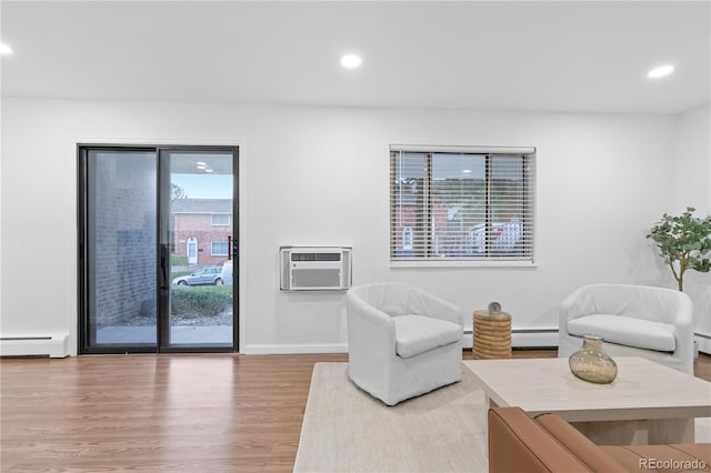 living room featuring a wall mounted air conditioner, wood-type flooring, a wealth of natural light, and baseboard heating