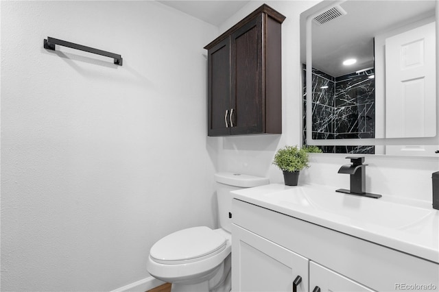 bathroom with tiled shower, vanity, and toilet