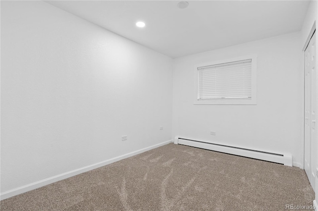 carpeted spare room with a baseboard heating unit