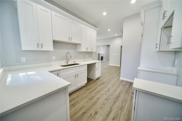 kitchen featuring white cabinetry, sink, and light wood-type flooring