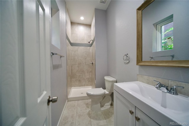 bathroom with tile patterned floors, vanity, toilet, and tiled shower