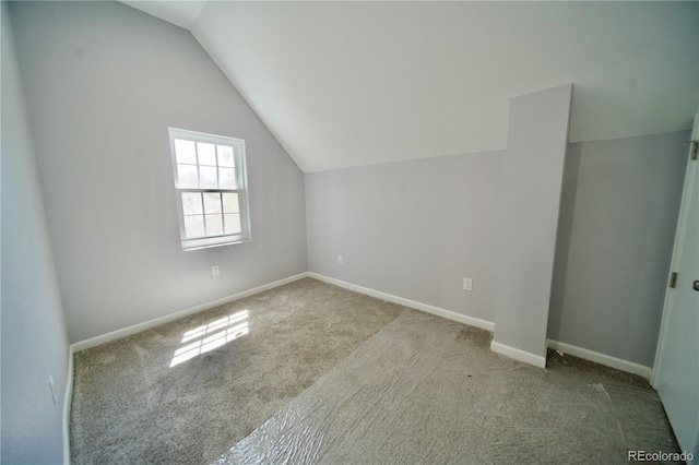 additional living space featuring light carpet and vaulted ceiling