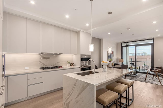 kitchen with a sink, light wood-style flooring, gas stovetop, and modern cabinets