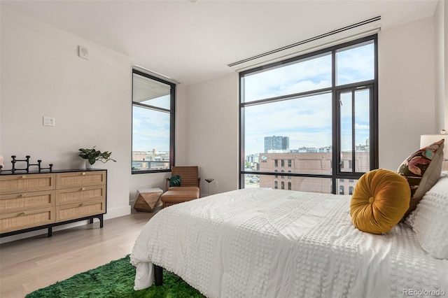 bedroom featuring light hardwood / wood-style flooring, a wall of windows, and multiple windows