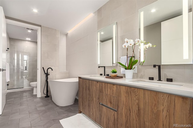 bathroom featuring double vanity, a soaking tub, a sink, a shower stall, and tile walls