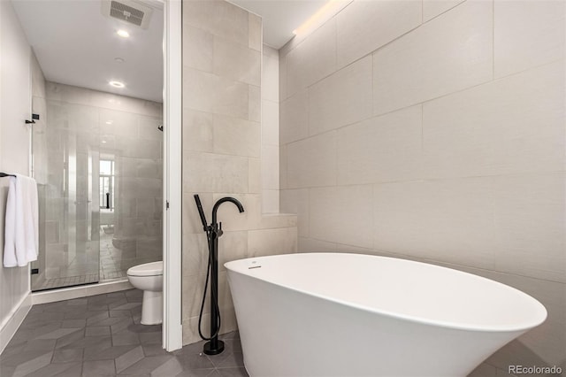 bathroom featuring tile patterned flooring, tile walls, toilet, and separate shower and tub