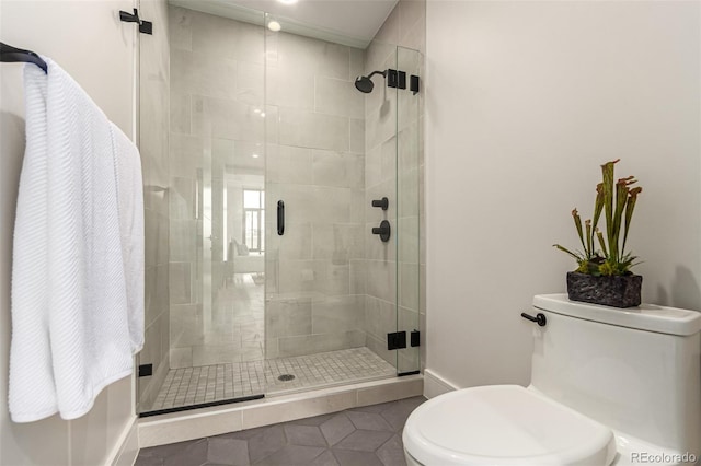 bathroom featuring tile patterned floors, toilet, and a shower with shower door