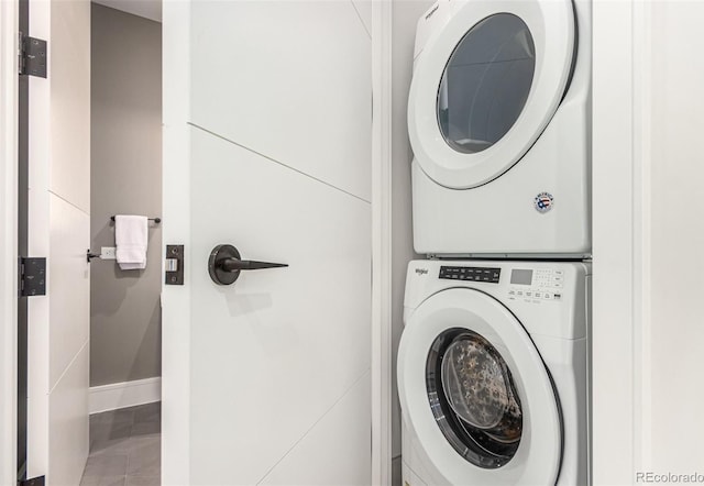 laundry area featuring laundry area, tile patterned flooring, baseboards, and stacked washer / drying machine