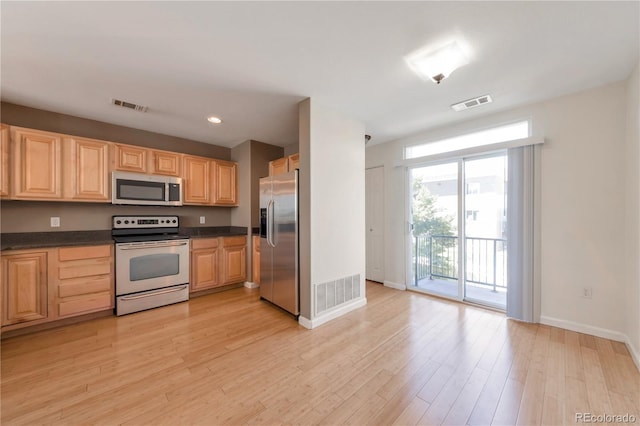 kitchen featuring dark countertops, light brown cabinetry, stainless steel appliances, and visible vents
